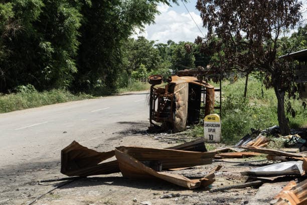 Burned vehicle and debris on a road in Manipur